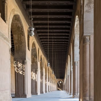 One of the passages surrounding the courtyard of public historic Mosque of Ahmad Ibn Tulun framed by huge decorated arches, old Cairo, Egypt