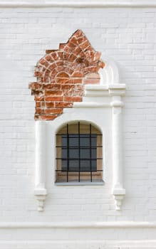 Rostov Veliky, Russia - September 13, 2021: close-up of a figured window with iron bars in the ancient restored white brick wall of the Stable Yard - part of the Rostov Kremlin. Medieval historical background.