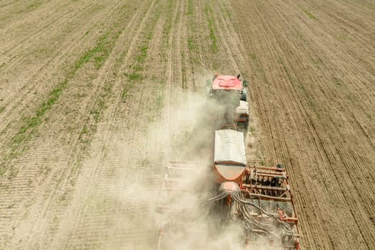 Aerial View. Tractor With Seed Drill Machine Sowing The Seeds For Crops In Spring Season. Beginning Of Agricultural Spring Season. Countryside Rural Field Landscape.