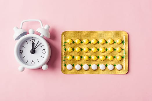 World sexual health or Aids day, Top view flat lay medicine birth control, alarm clock and contraceptive pills, studio shot isolated on a pink background, Safe sex and reproductive health concept