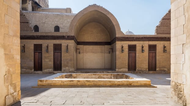 Courtyard of public historic mosque of Sultan Al Nassir Qalawun with side arched iwan and closed wooden doors, Cairo, Egypt