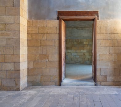 Open wooden door in bricks stone wall revealing vacant room with bricks wall, Old Cairo, Egypt