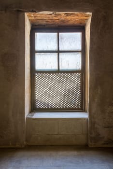 Single Interleaved grunge wooden ornate window - Mashrabiya - in stone wall at abandoned building, Medieval Cairo, Egypt