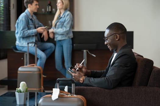 Businessman sitting on sofa at the airport lounge, waiting for the flight. Smiling man using digital tablet for presentation or new ideas of business project.