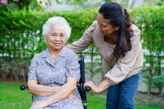 Caregiver help Asian elderly woman disability patient sitting on wheelchair in park, medical concept.