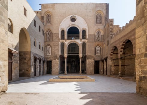 Main Iwan at courtyard of public historic mosque of Sultan Qalawun with huge arches, wooden doors and decorated windows, Cairo, Egypt