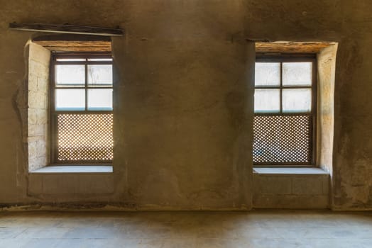 Two Interleaved grunge wooden ornate windows - Mashrabiya - in stone wall at abandoned building, Medieval Cairo, Egypt
