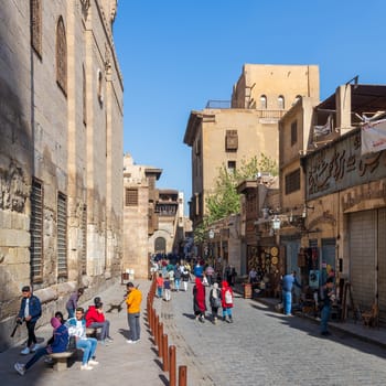 Cairo, Egypt- December 14 2019: Moez Street with local visitors Mosque of Sultan Barquq and Sabil-Kuttab of Katkhuda historic building at the far end, Gamalia district, Old Cairo