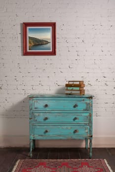 White brick wall with shabby chic vintage turquoise cabinet and hanged painting in living room, with clipping path for the painting