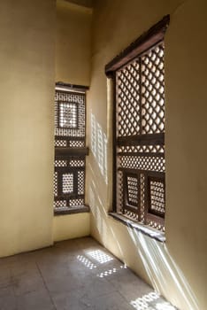 Corner of two Interleaved grunge wooden ornate windows - Mashrabiya - in stone wall at abandoned building