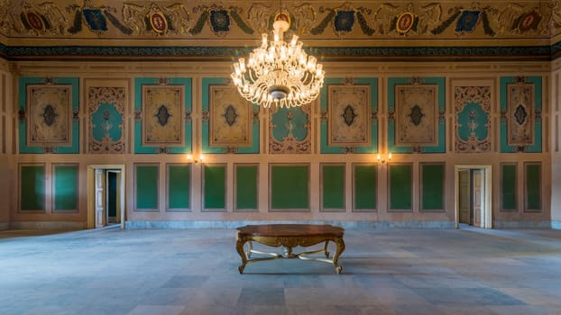 Royal era historic Manasterly Palace with beautiful elegant carved frames on green wall with ornate borders, floral decorated ceiling, chandelier, and marble floor, Cairo, Egypt