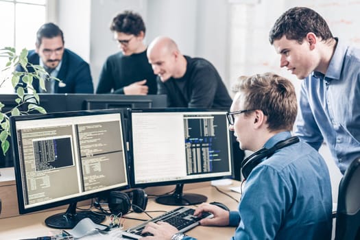 Startup business and entrepreneurship problem solving. Young AI programmers and IT software developers team brainstorming and programming on desktop computer in startup company share office space.