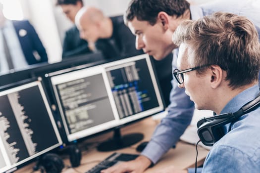 Startup business and entrepreneurship problem solving. Young AI programmers and IT software developers team brainstorming and programming on desktop computer in startup company share office space.