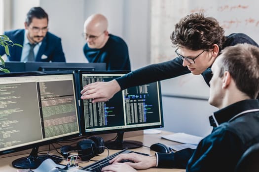 Startup business and entrepreneurship problem solving. Young AI programmers and IT software developers team brainstorming and programming on desktop computer in startup company share office space.