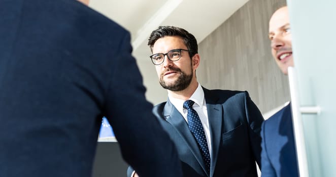 Group of confident business people greeting with a handshake at business meeting in modern office. Closing the deal agreement by shaking hands. Business and entrepreneurship success concept.