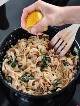 Woman squeeze a lemon on tasty home made seafood pasta in home kitchen, Closeup shot.