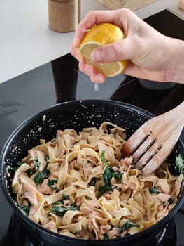 Woman squeeze a lemon on tasty home made seafood pasta in home kitchen, Closeup shot.