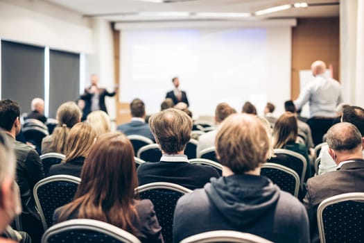 I have a question. Group of business people sitting at the chairs in conference hall. Businessman standing up asking a question. Conference and Presentation. Business and Entrepreneurship.