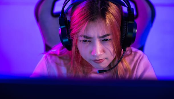 Young woman wearing gaming headphones intend to do playing live stream games online at home, Happy Gamer endeavor plays online video games tournament with computer neon lights