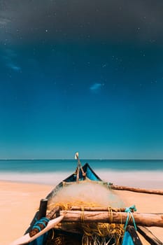 Goa, India. Real Night Sky Stars. Natural Starry Sky Blue Color Above Sea Seascape Ocean Beach. Background. Parked Old Wooden Boat At Coast.