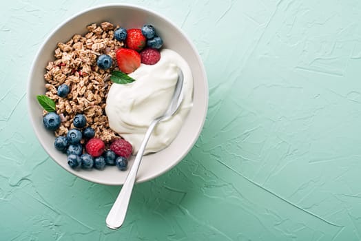 A plate of dry granola served with fresh berry fruit and yogurt. Oatmeal plate. Healthy food, diet. Top view.