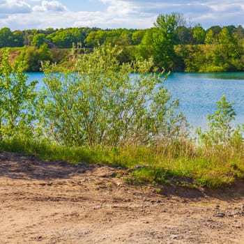 Beautiful quarry lake dredging pond lake with blue turquoise water blue sky and landscape nature forest panorama view in Eggestedt Schwanewede Osterholz Lower Saxony Germany.