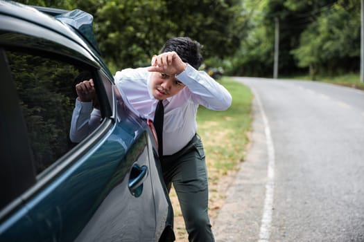 Asian businessman car broken has problems with car down during go to work in morning he pushing out of gas on road at countryside, business man have trouble roadside, problem transportation