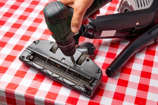 Repair of household appliances. Professional technician repairs a vacuum cleaner. Household appliances customer service. Battery hoover. Repair by a specialist on site.
