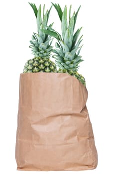 Closeup of a brown paper shopping bag with fresh ripe pineapple fruits isolated on a white background. Concept of strengthening the immune system. Healthy nutrition. Tropical fruits.