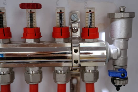 Heating system manifold valves for heat flooring and water supply in a country house. Pipes collector in a building under construction.