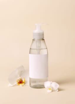 Cosmetic pump dispenser bottle near white orchid flowers on light beige close up, mockup. Skincare beauty product package. Exotic natural cosmetics, pastel minimal composition..