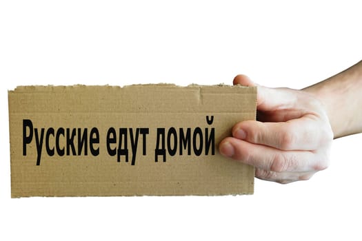 Sign from cardboard in Russian language in one hand with inscription Russians go home