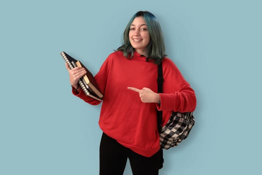 Cute young gilr student with blue hair books and a backpack over a cyan background