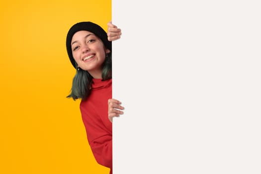 Lovely young girl holding a big blank board over yellow background