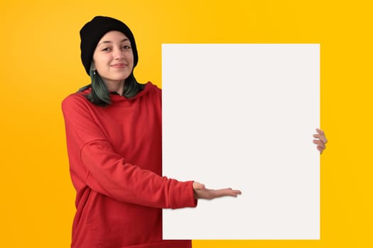 Lovely young girl holding a big blank board over yellow background