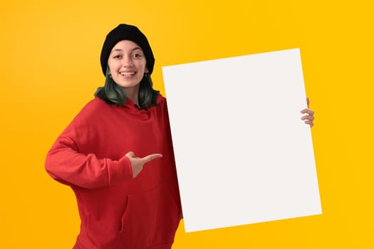 Lovely young girl holding a big blank board over yellow background