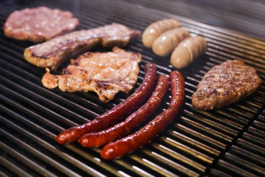 Different grilled barbecue meats, sausages, hamburger and chicken are baking on the grill.