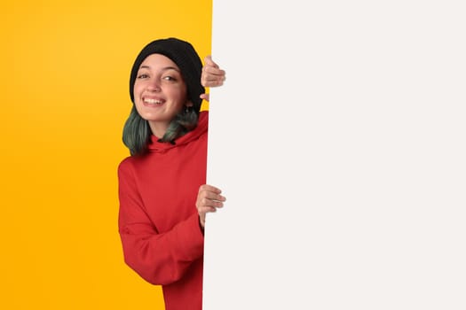 Lovely young girl holding a big blank board over yellow background