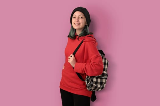 Cute young gilr student with blue hair and a backpack isolated over pink background