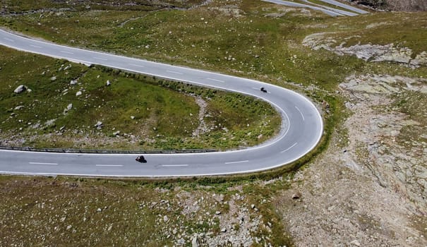 Aerial drone shot of tight curve with motorcyclist in mountains