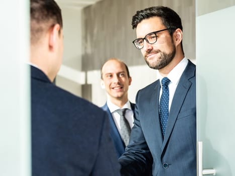Group of confident business people greeting with a handshake at business meeting in modern office. Closing the deal agreement by shaking hands. Business and entrepreneurship success concept.