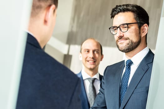Group of confident business people greeting with a handshake at business meeting in modern office. Closing the deal agreement by shaking hands. Business and entrepreneurship success concept.