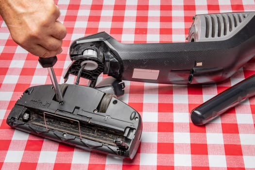 Repair of household appliances. Professional technician repairs a vacuum cleaner. Household appliances customer service. Battery hoover. Repair by a specialist on site.