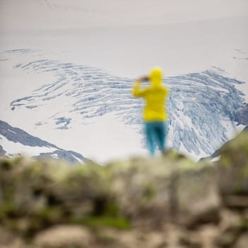 Young woman admiring the natural beauty of a glacier in the Swiss Alps. Europe