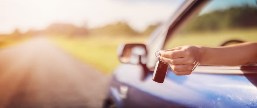 Woman's hand holding key from her new car. Concept of buying and selling ofthe automobile.