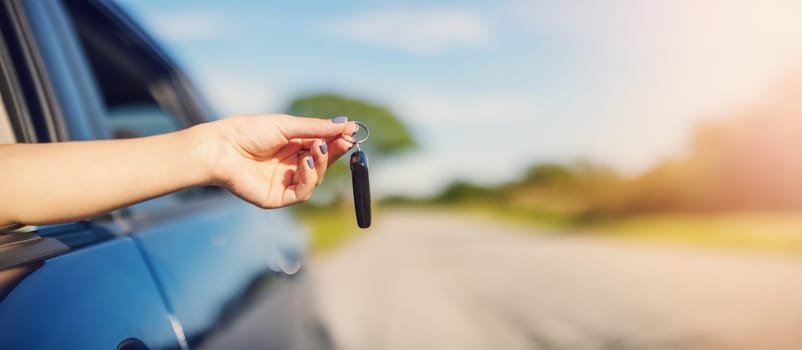 Woman's hand holding key from her new car. Concept of buying and selling ofthe automobile.