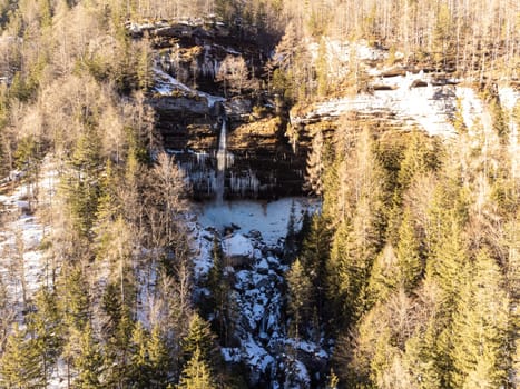 Aerial view of Pericnik slap or Pericnik Waterfall in winter time, Triglav National Park, Slovenia. Upper and lower waterfalls cascading over a rocky cliff, reachable by a picturesque walking trail