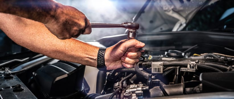 Auto mechanic working on car engine in mechanics garage. Repair service. authentic close-up shot - selective focus