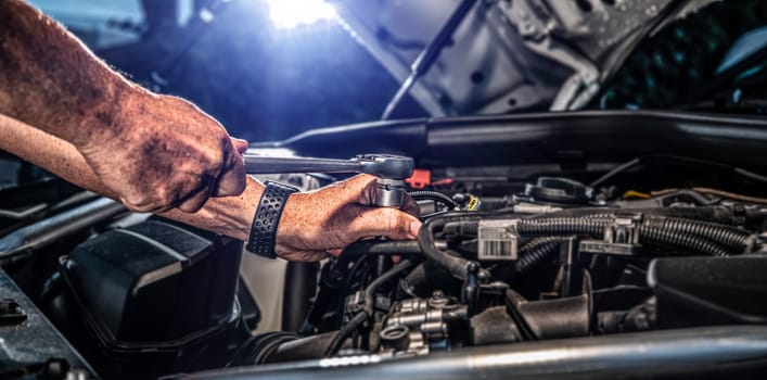 Auto mechanic working on car engine in mechanics garage. Repair service. authentic close-up shot - selective focus