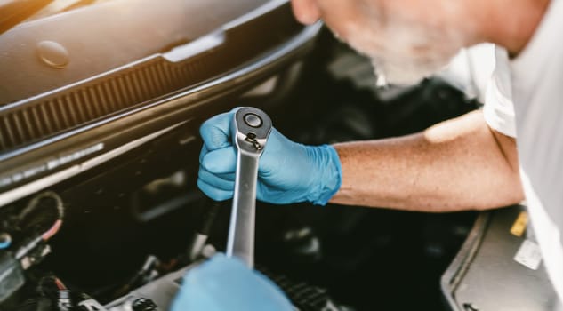Auto mechanic working on car engine in mechanics garage. Repair service. authentic close-up shot - selective focus